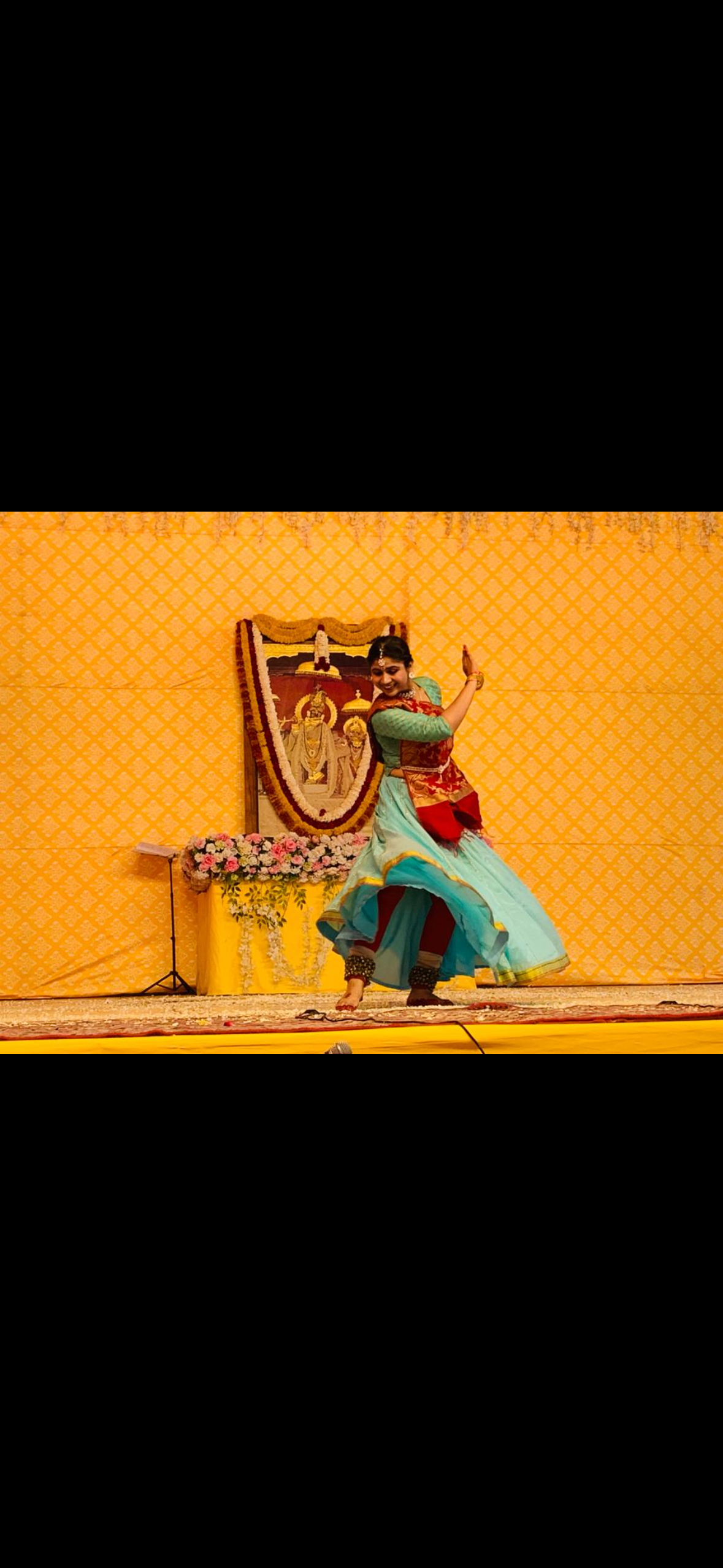 Surbhi performing on stage before a temple-style backdrop